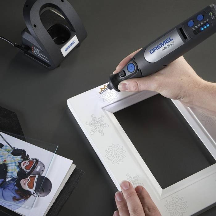person using a cordless dremel rotary tool to engrave a picture frame